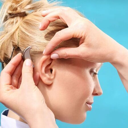 Junger Frau wird ein Hörgerät angebracht